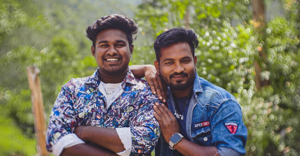 Two adult men smiling and posing together outdoors, showcasing friendship and joy.